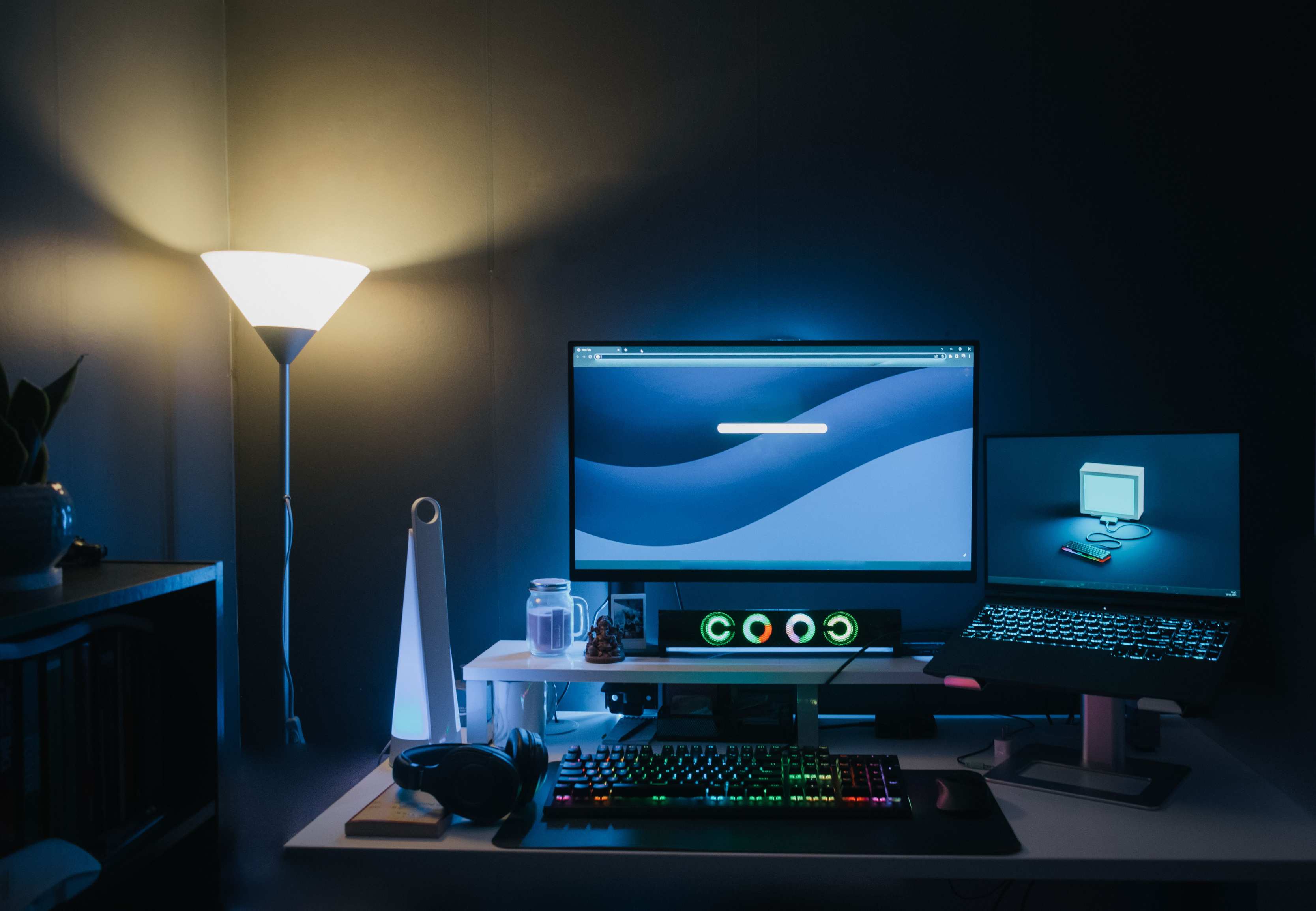 Laptop and external monitor on a desk in a city-facing workspace with street light through the window